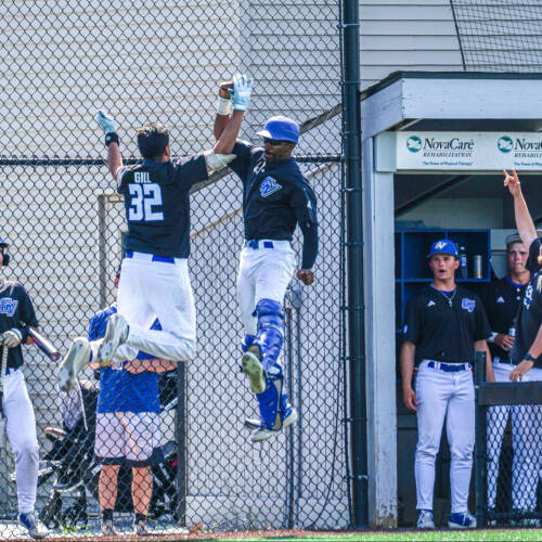 Men's Baseball high-five's in the air from 2026 season.